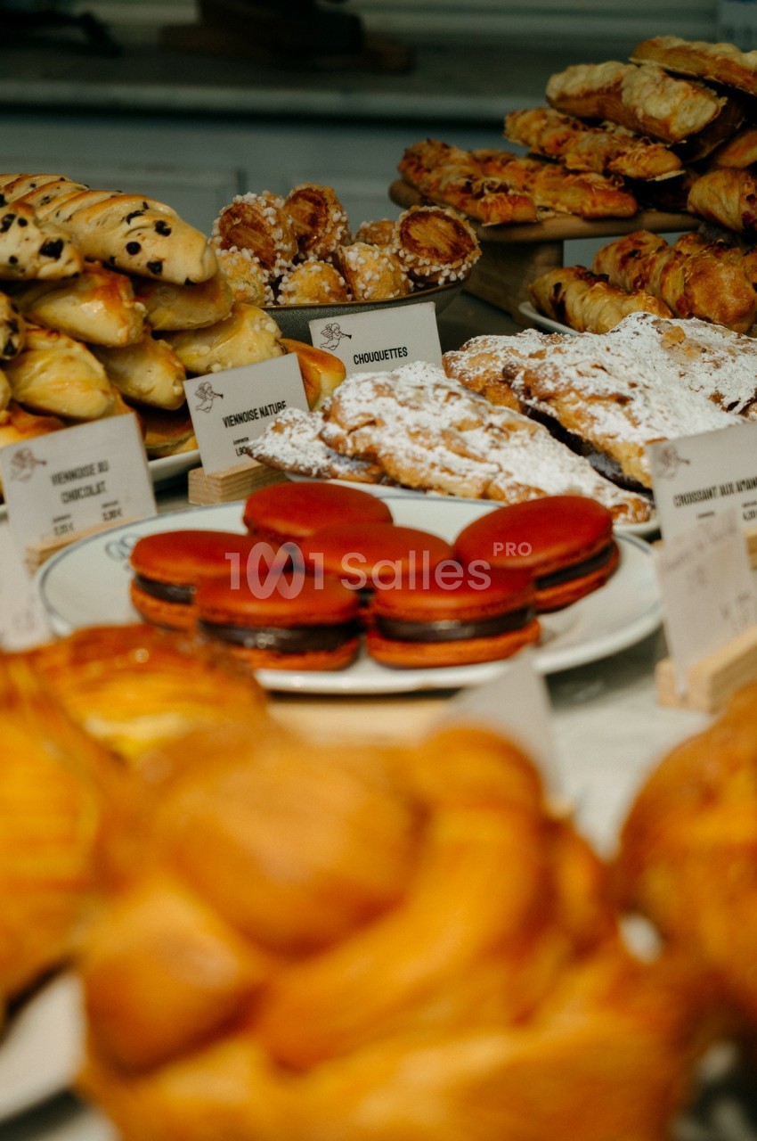 Assortiment de viennoiseries et pâtisseries variées présentées sur un comptoir, dont macarons et croissants.
