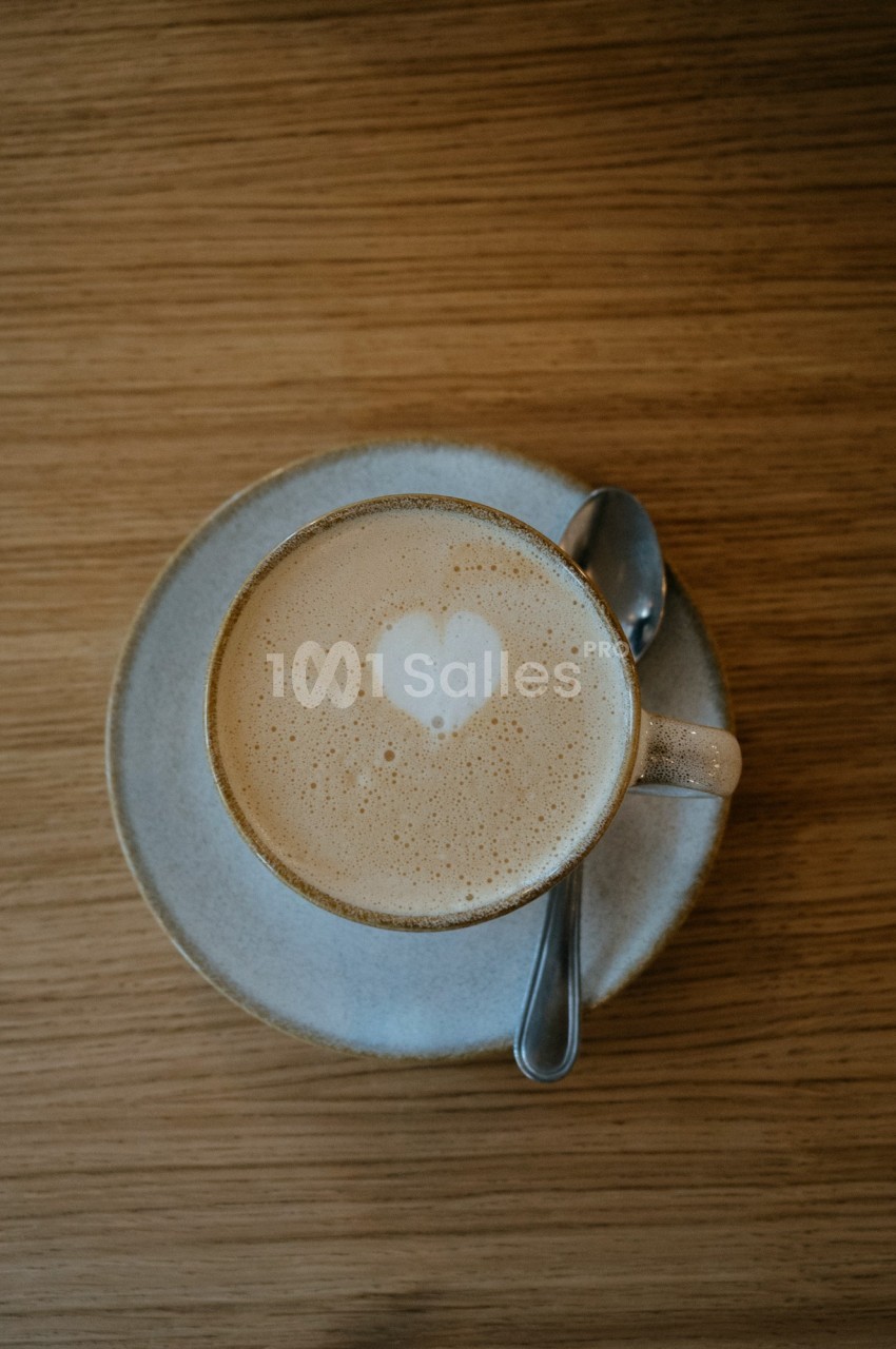Tasse de café latte avec un motif en forme de cœur dans la mousse, posée sur une soucoupe avec une cuillère.