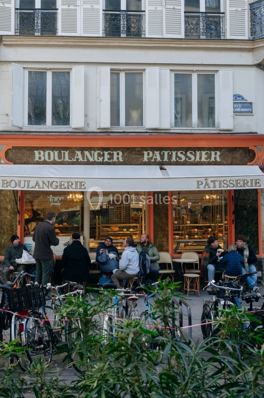 Façade d'une boulangerie-pâtisserie avec des clients assis en terrasse et des vélos stationnés devant.