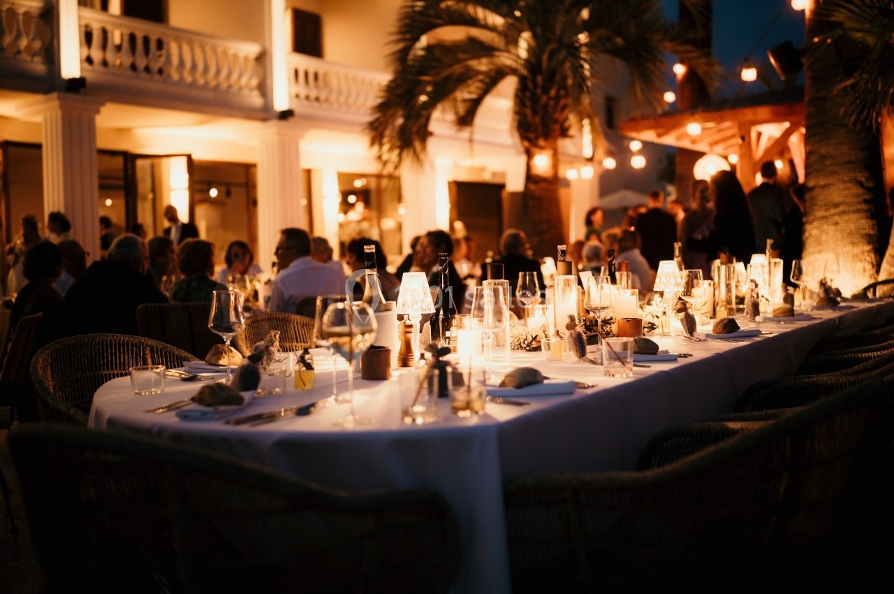 Dîner en plein air à la tombée de la nuit, avec des tables élégamment dressées et une ambiance lumineuse chaleureuse.