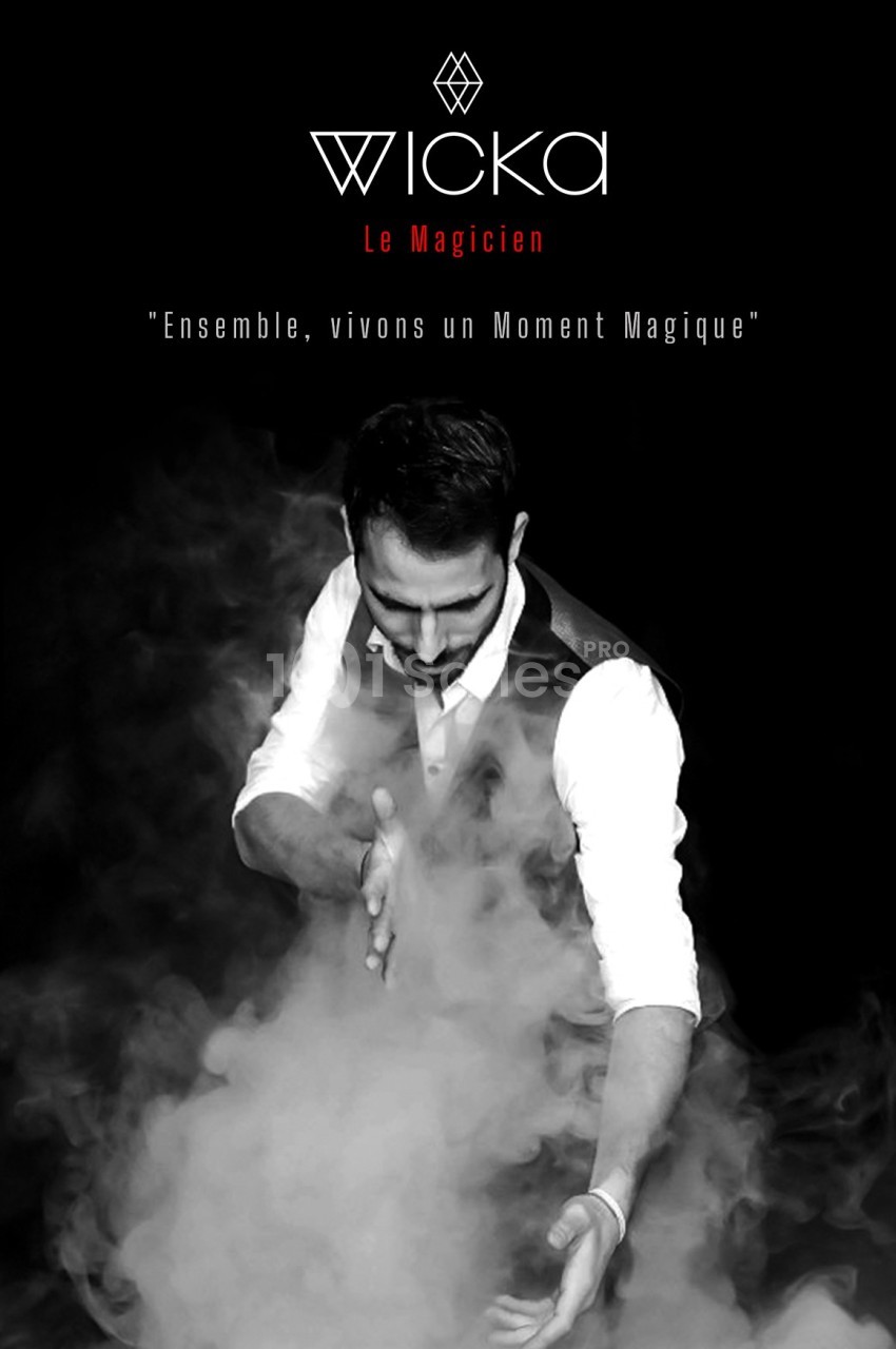 Un magicien en costume manipule de la fumée dans une ambiance sombre et mystérieuse.