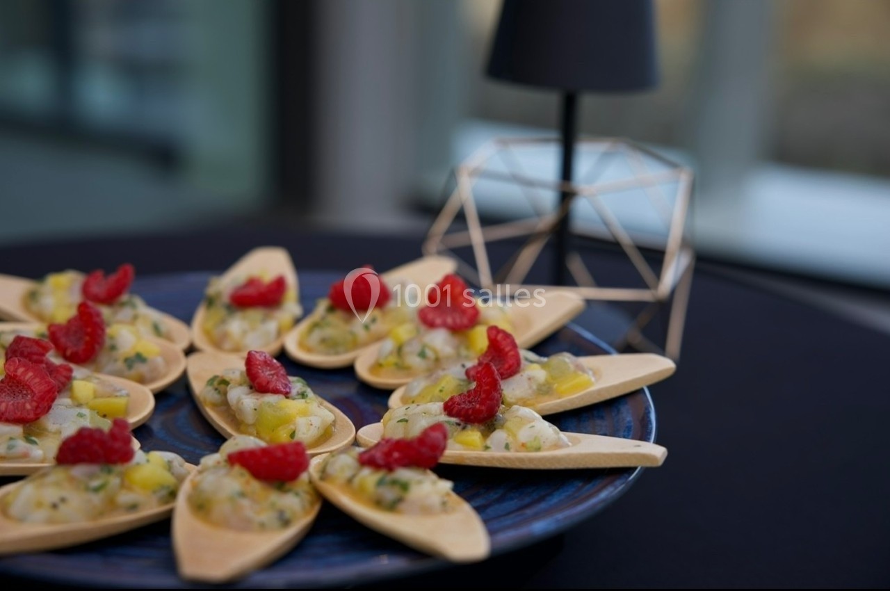 Assortiment de bouchées apéritives sur des cuillères en bois, garnies de fruits rouges et d'une préparation crémeuse.