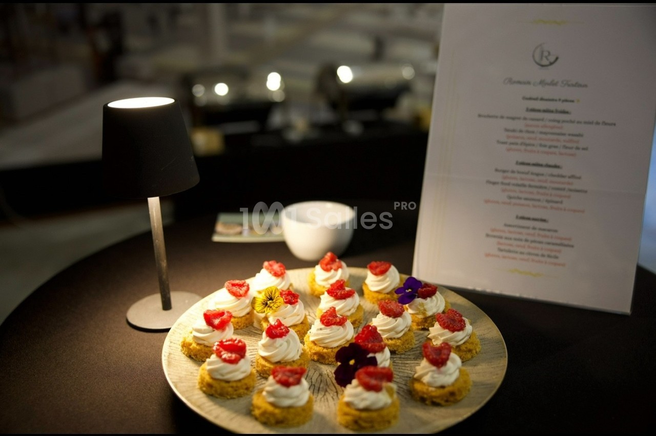 Assortiment de desserts individuels décorés de framboises et fleurs comestibles, présenté sur une table sombre.