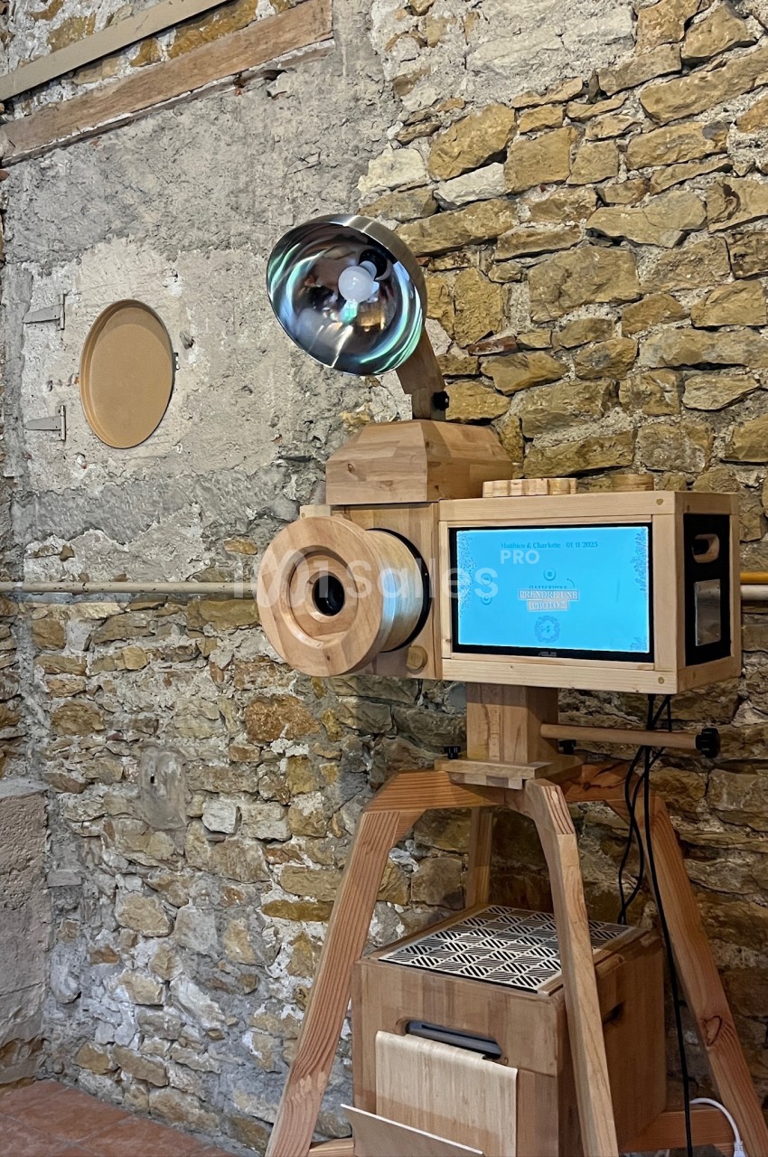 Machine en bois avec écran tactile et lampe, installée devant un mur en pierre dans un espace intérieur rustique.