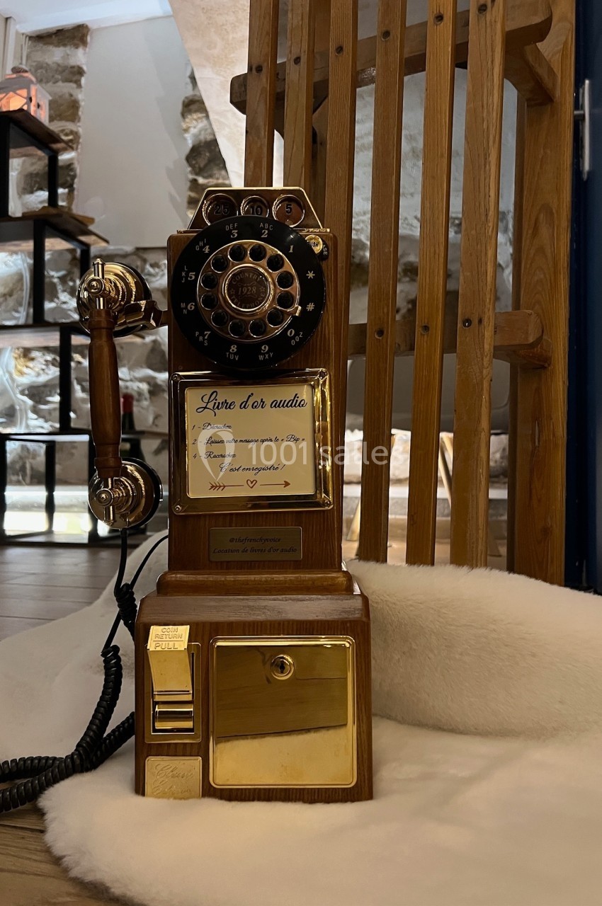 Téléphone rétro doré à cadran rotatif posé sur une surface blanche, avec un décor en bois et pierre en arrière-plan.
