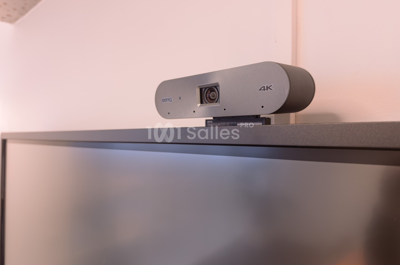 Webcam 4K posée sur le bord supérieur d'un écran d'ordinateur dans un environnement intérieur.