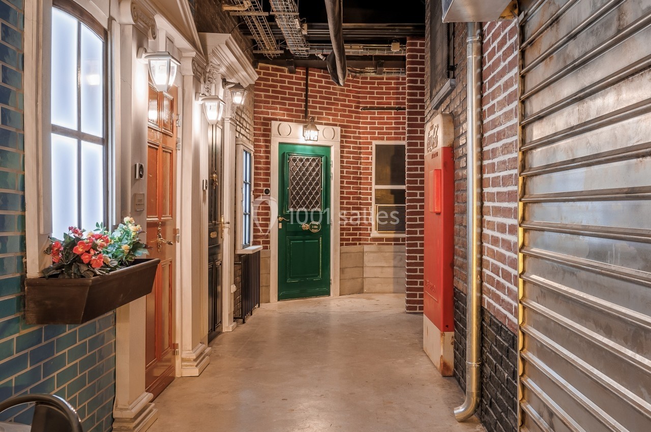 Couloir intérieur avec façades imitant des devantures de maisons, portes colorées et décorations urbaines.