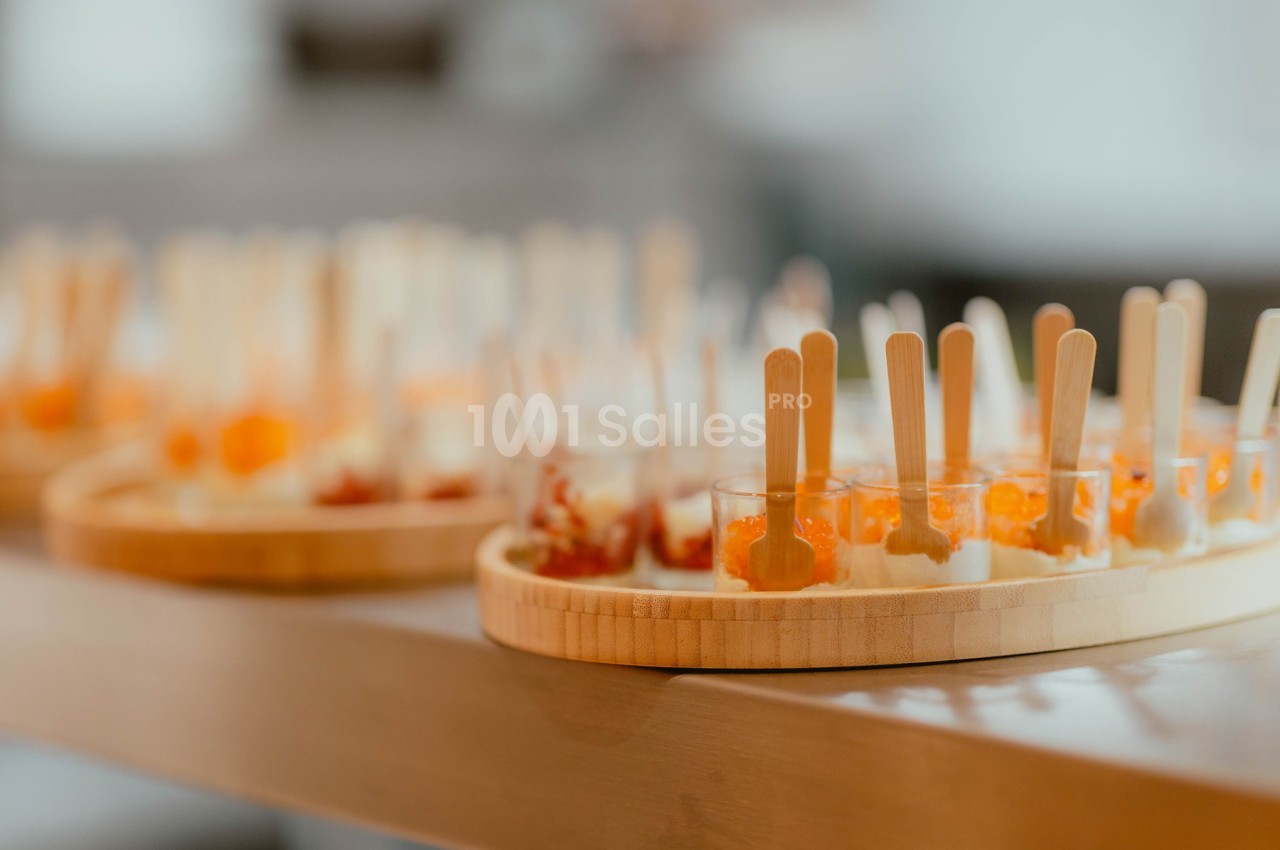 Plateaux en bois garnis de verrines colorées avec des cuillères en bois, disposés sur une table.