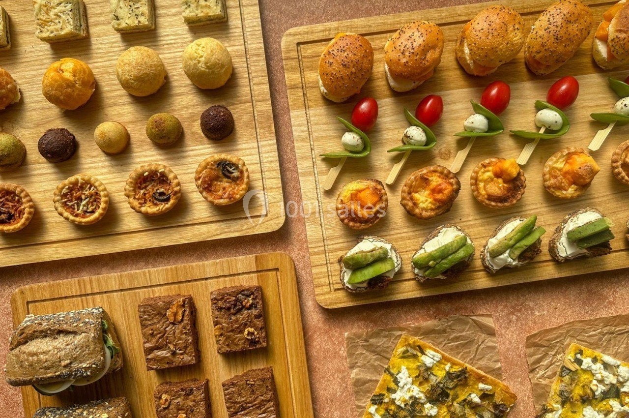Plateaux en bois garnis de bouchées salées variées, incluant mini-sandwichs, brochettes et tartines.