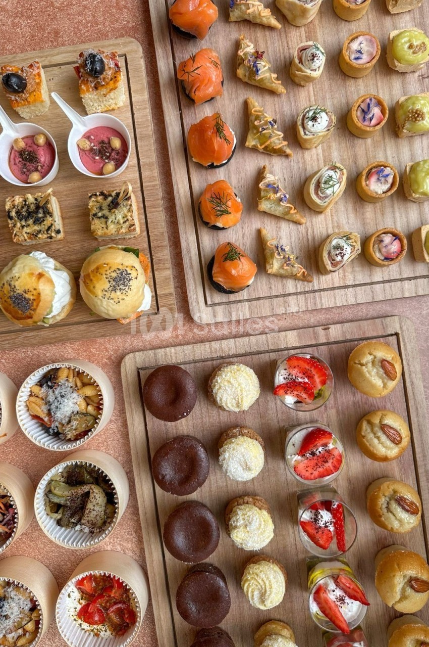 Plateaux en bois garnis de bouchées salées et sucrées variées, présentées pour un buffet ou un événement.