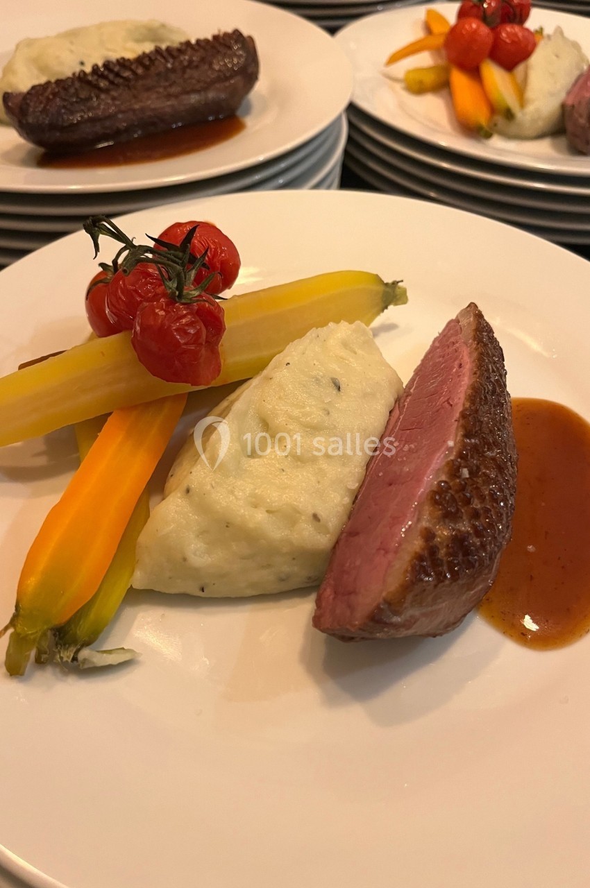 Assiette composée de magret de canard, purée, carottes colorées, tomates cerises et sauce brune.