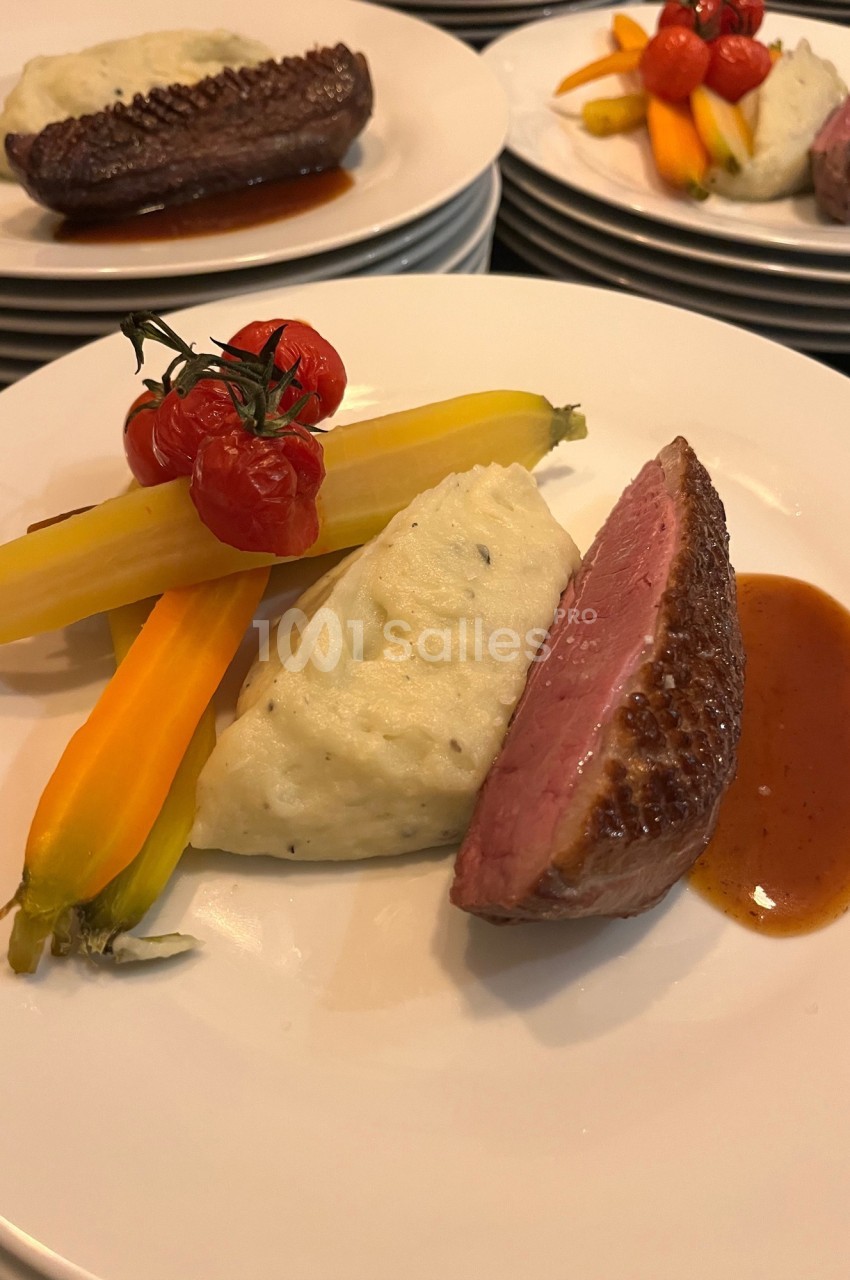 Assiette composée de magret de canard, purée, carottes colorées, tomates cerises et sauce brune.