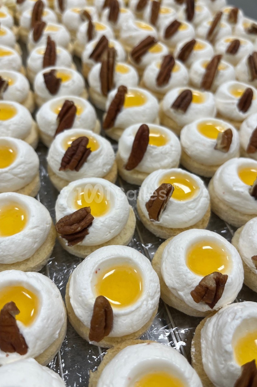 Petits desserts individuels garnis de crème, gelée jaune et décorés de morceaux de noix de pécan.