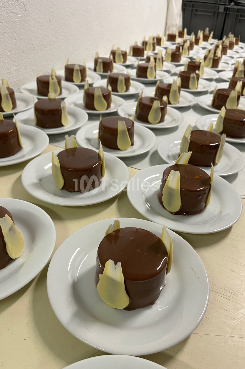 Desserts individuels enrobés de chocolat brillant, décorés de morceaux de chocolat blanc, disposés sur des assiettes…