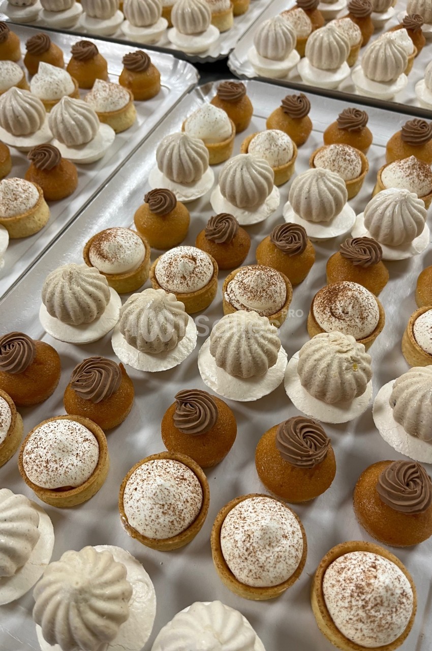 Plateaux de petits desserts variés, incluant des meringues, des choux et des bouchées garnies de crème.
