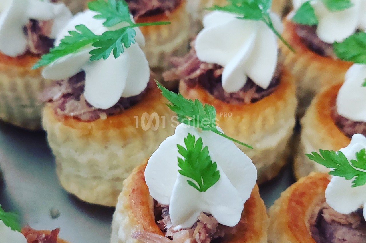 Bouchées feuilletées garnies de viande effilochée, crème décorative et feuilles de persil frais.