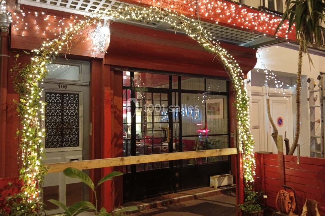 Devanture d'un restaurant avec une arche lumineuse décorative et des plantes, prise de nuit.