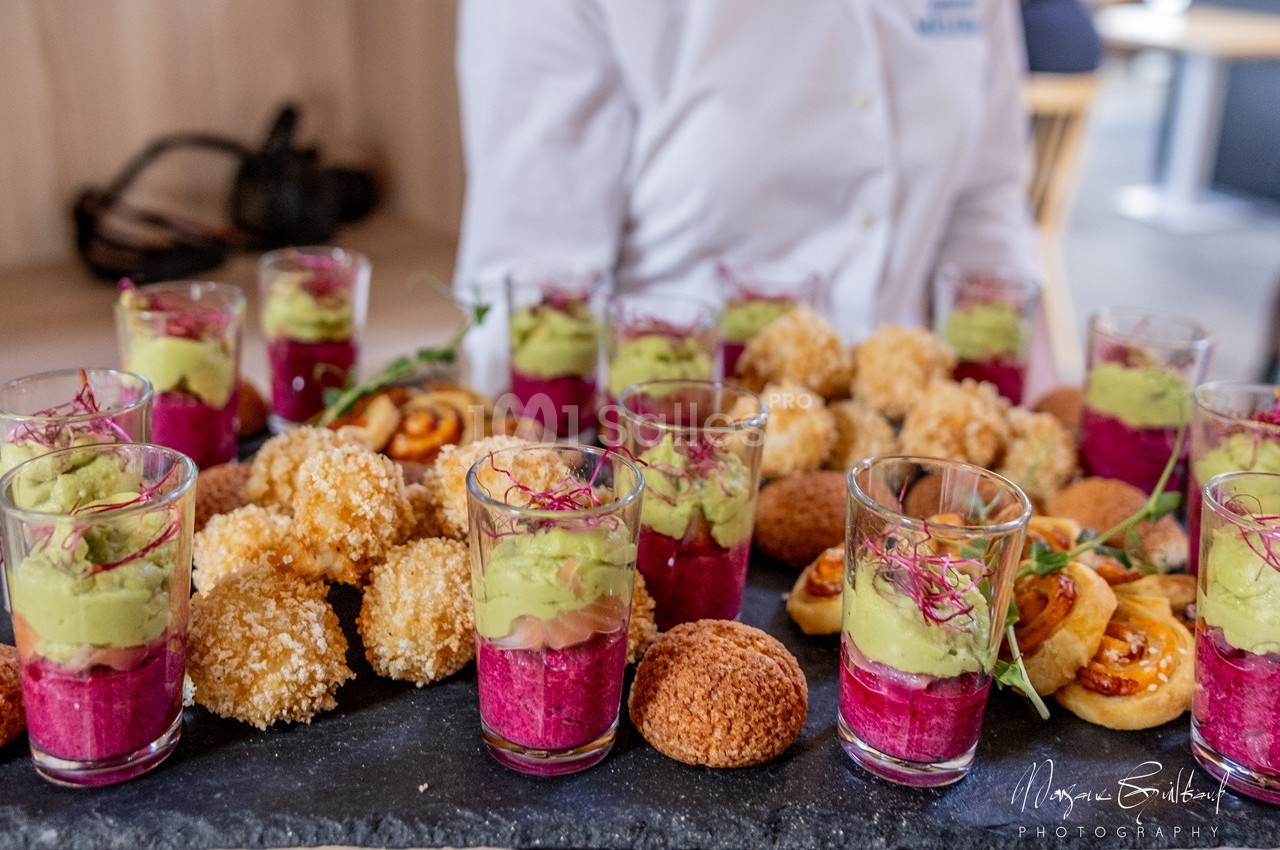 Plateau de verrines colorées avec mousse d'avocat et betterave, accompagné de bouchées salées variées.