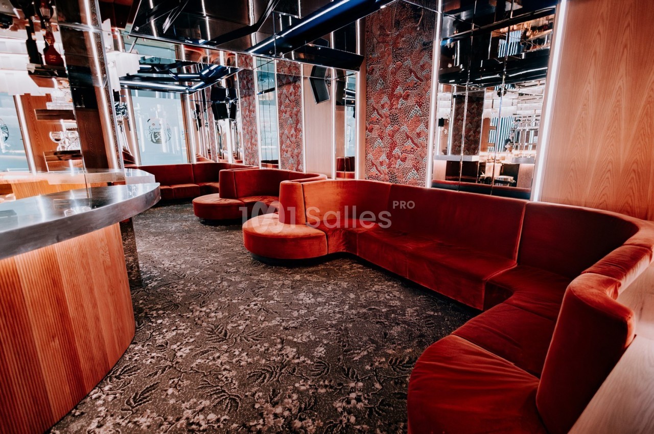 Banquettes en velours rouge disposées en arc de cercle dans un intérieur moderne avec murs en bois et miroirs.