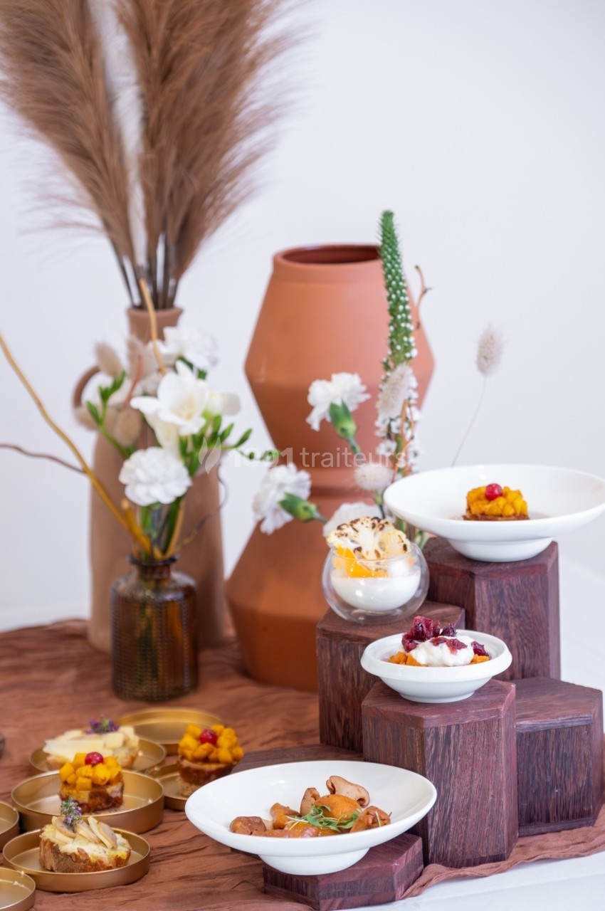 Présentation de plats gastronomiques dans des assiettes blanches sur des supports en bois, avec une décoration florale en…