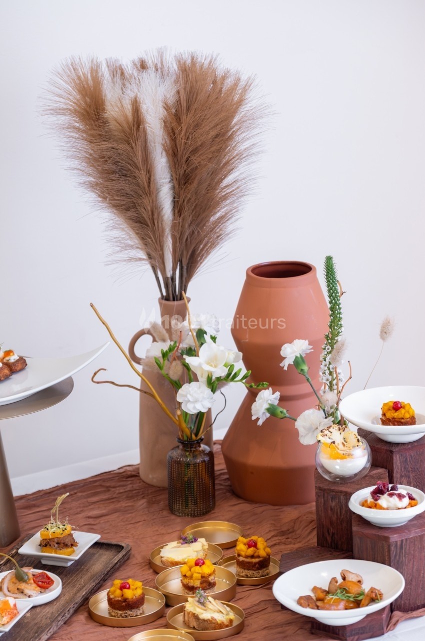 Assortiment de desserts présentés sur des supports variés, décorés avec des fleurs et des vases en arrière-plan.