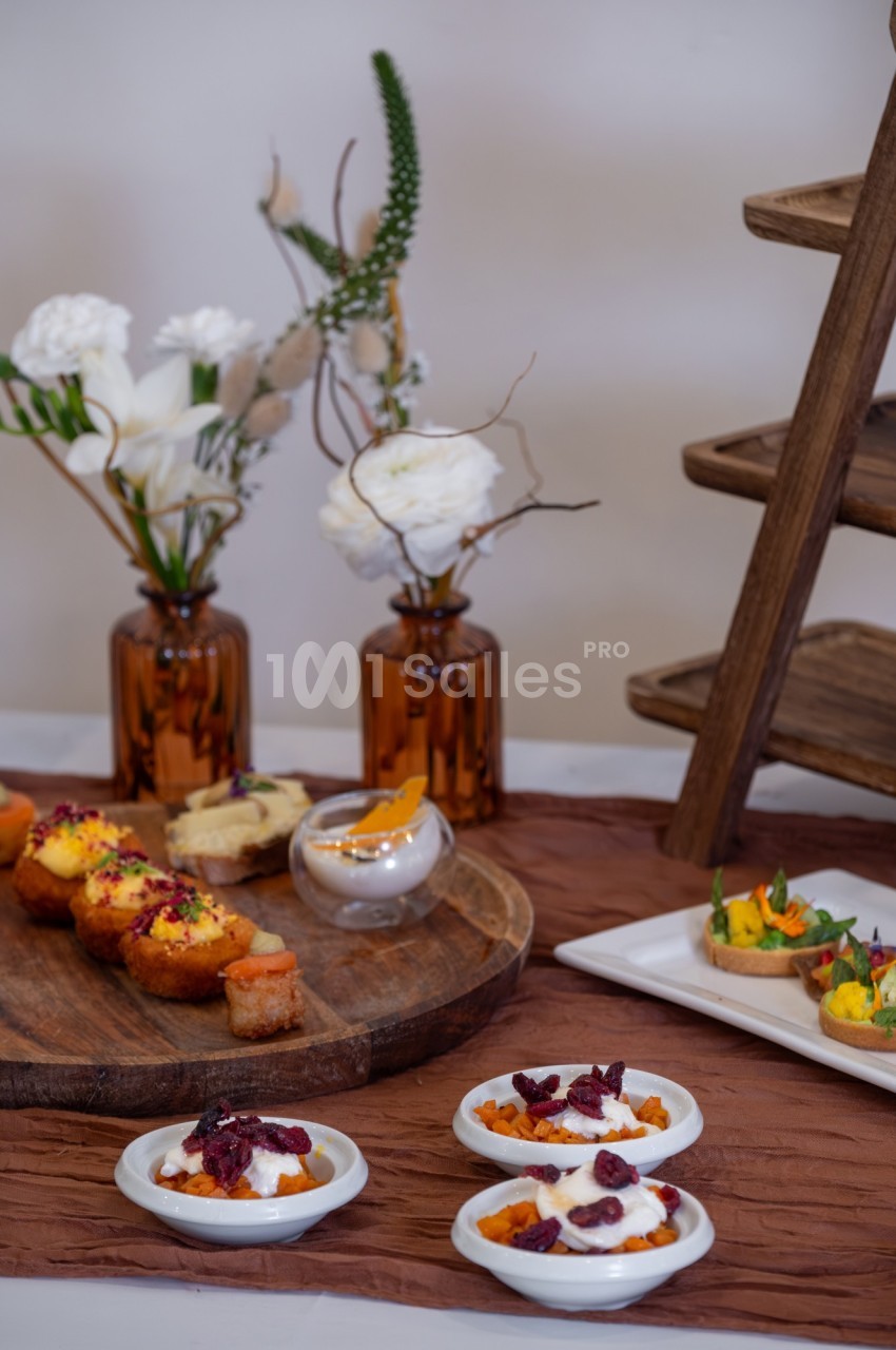 Plateau de desserts variés et verrines, disposés sur une table avec des fleurs blanches en arrière-plan.