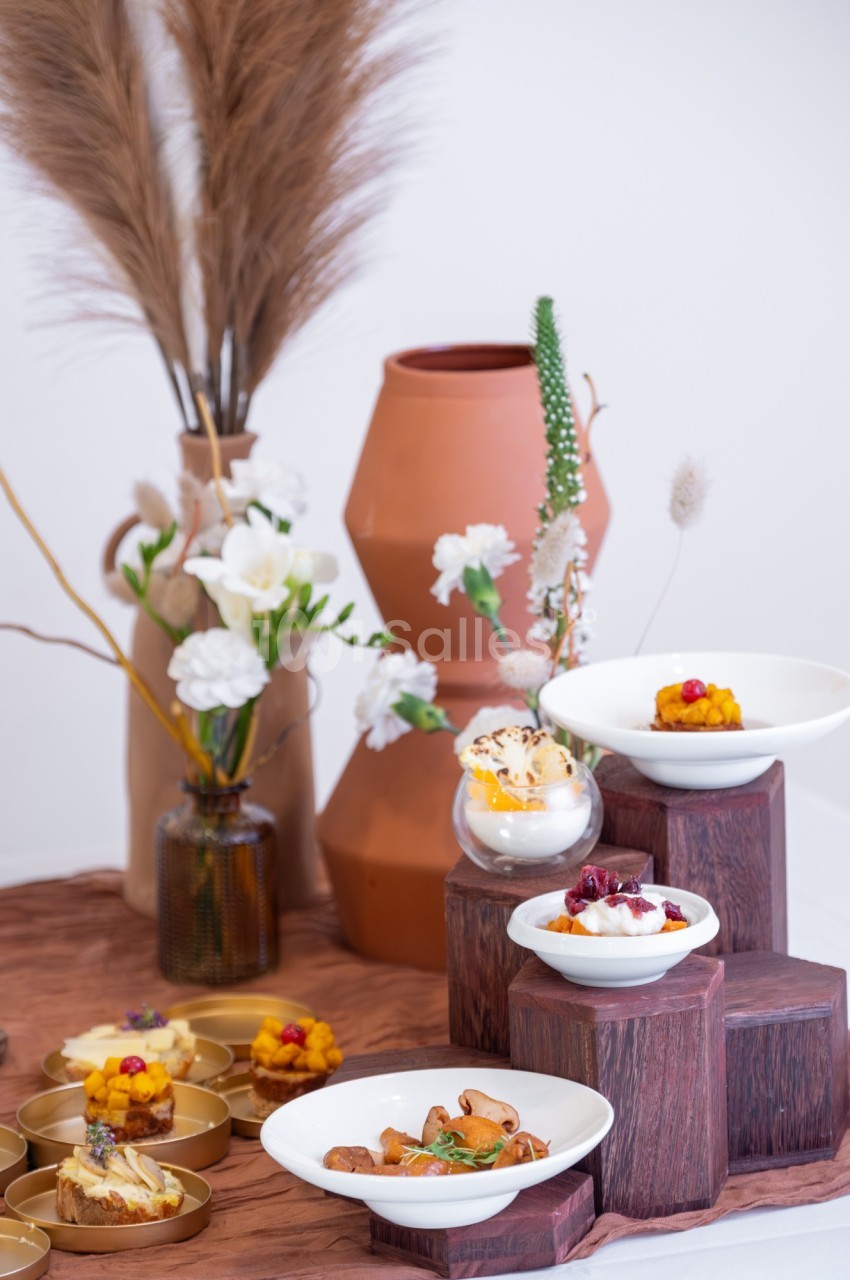 Présentation de plats gastronomiques dans des assiettes blanches sur des supports en bois, avec une décoration florale en…