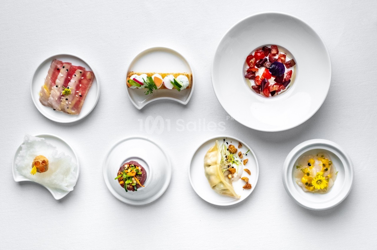 Assortiment de plats gastronomiques présentés dans des assiettes blanches sur une table blanche.