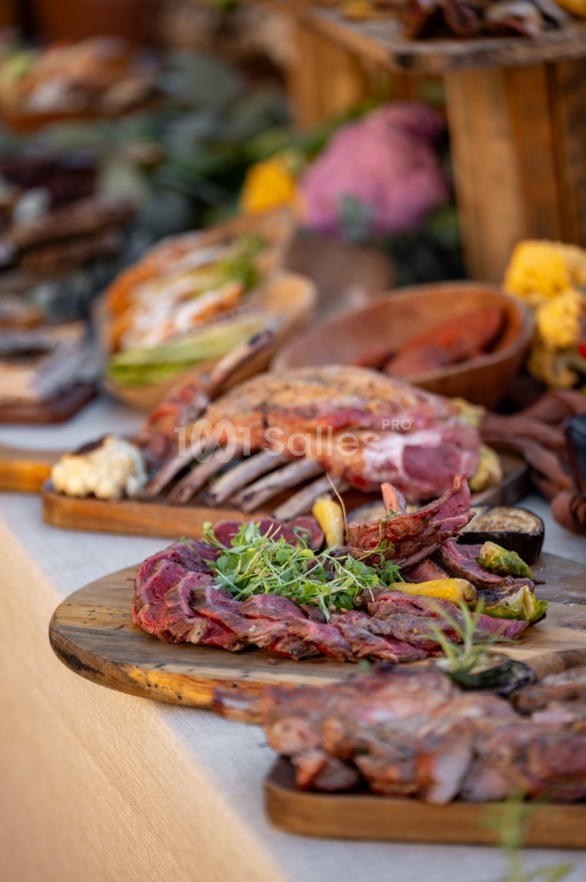Plateaux de viandes grillées et tranchées, garnis d'herbes fraîches, présentés sur des planches en bois.