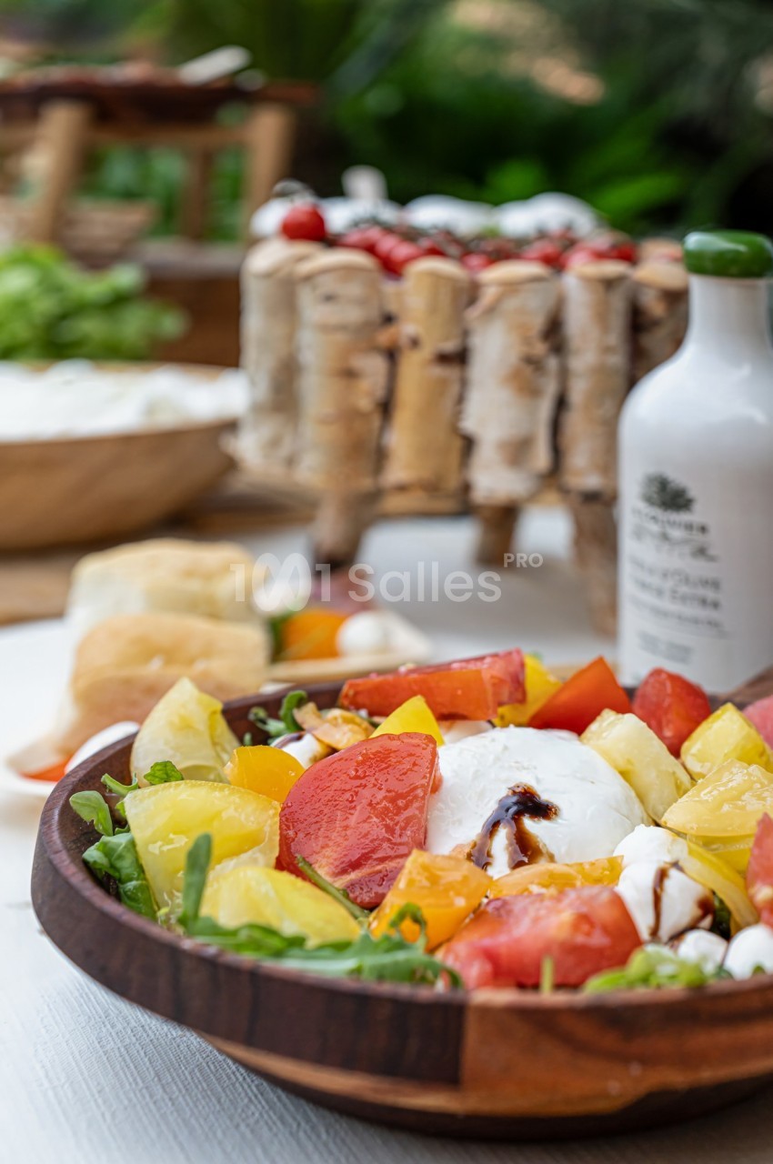 Salade colorée avec tomates, mozzarella, roquette et vinaigre balsamique, présentée dans un bol en bois.