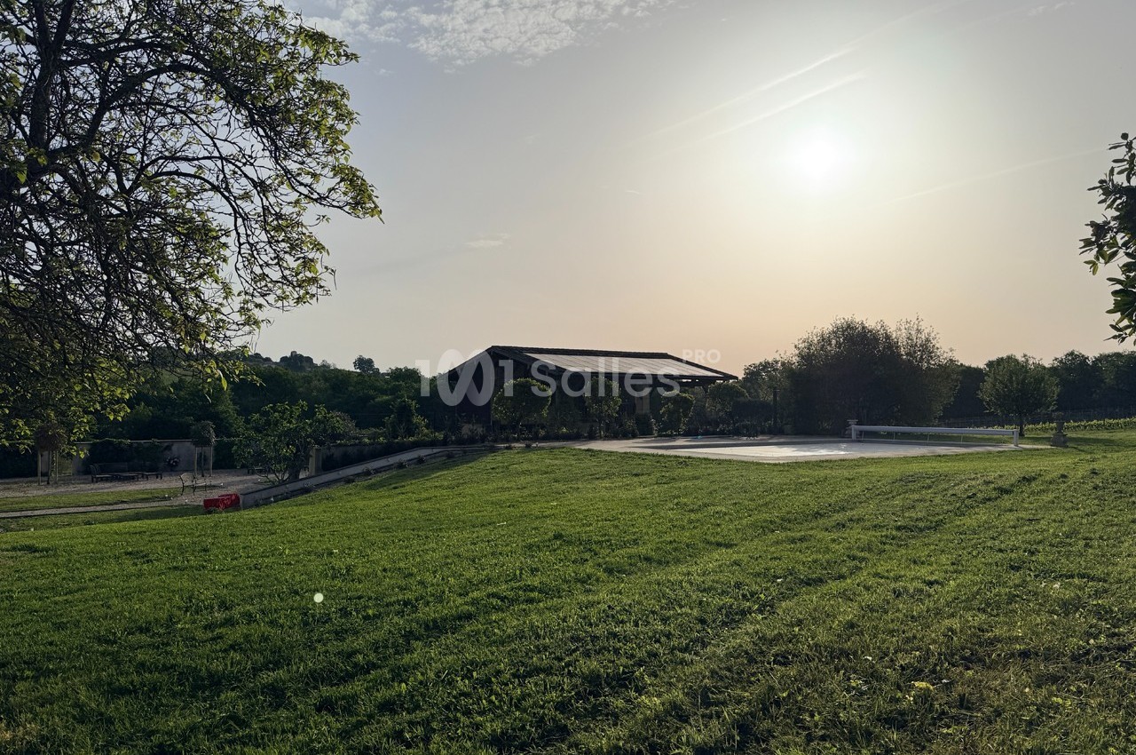 Pelouse verdoyante au coucher du soleil avec une piscine couverte et un bâtiment en arrière-plan.