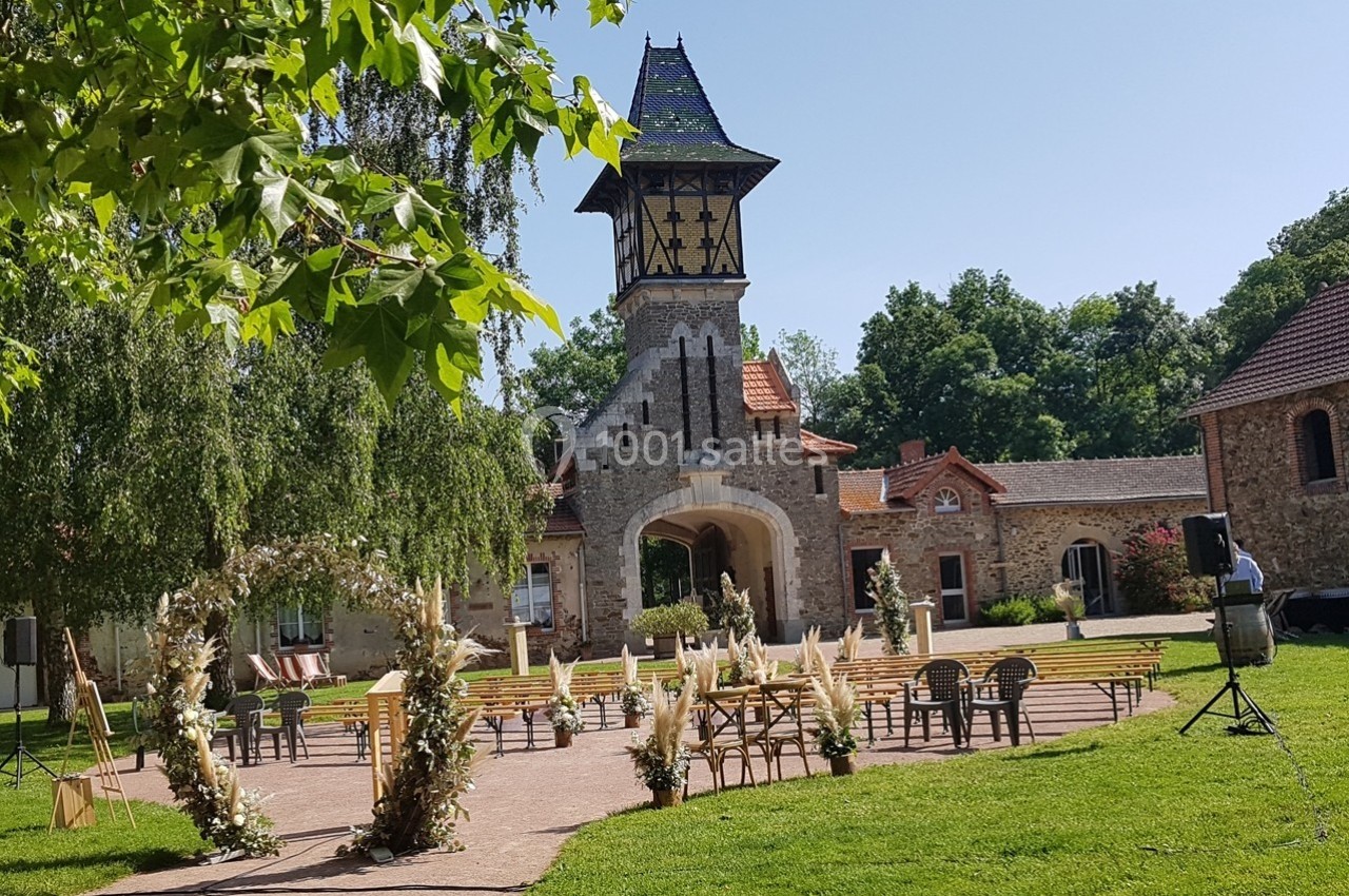 Cour extérieure d'un bâtiment en pierre avec une tour, aménagée pour une cérémonie avec des chaises et des décorations…