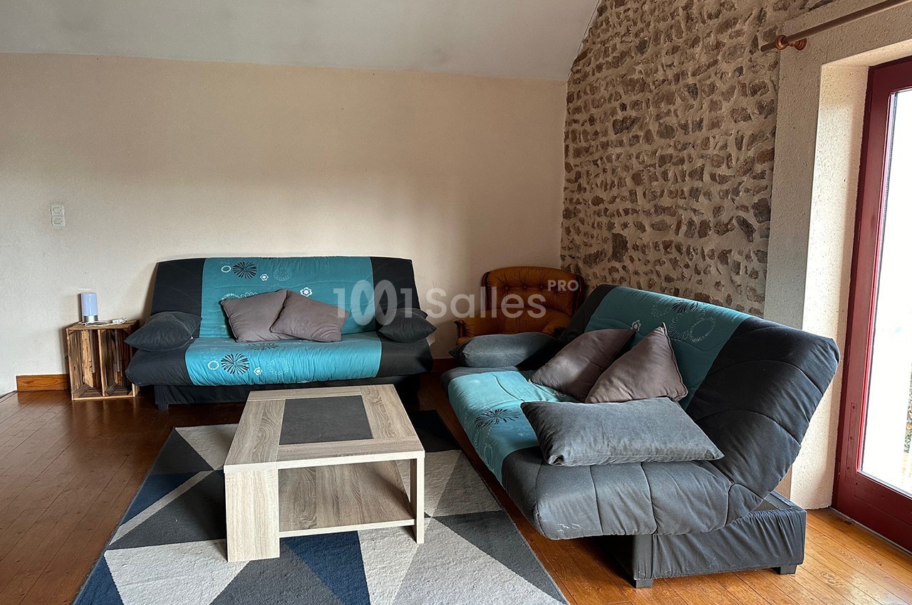 Deux canapés noirs et bleus avec coussins, une table basse en bois clair, sur un tapis géométrique dans un salon.