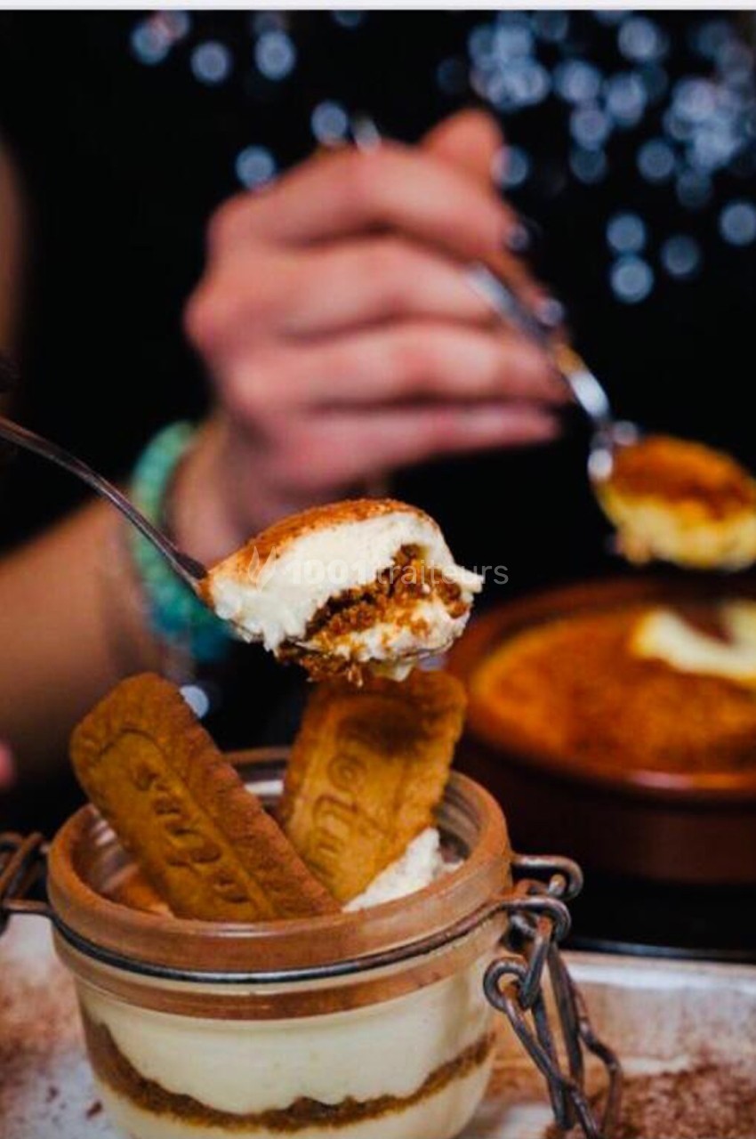 Deux personnes dégustent des desserts, dont un tiramisu en bocal garni de biscuits spéculoos.