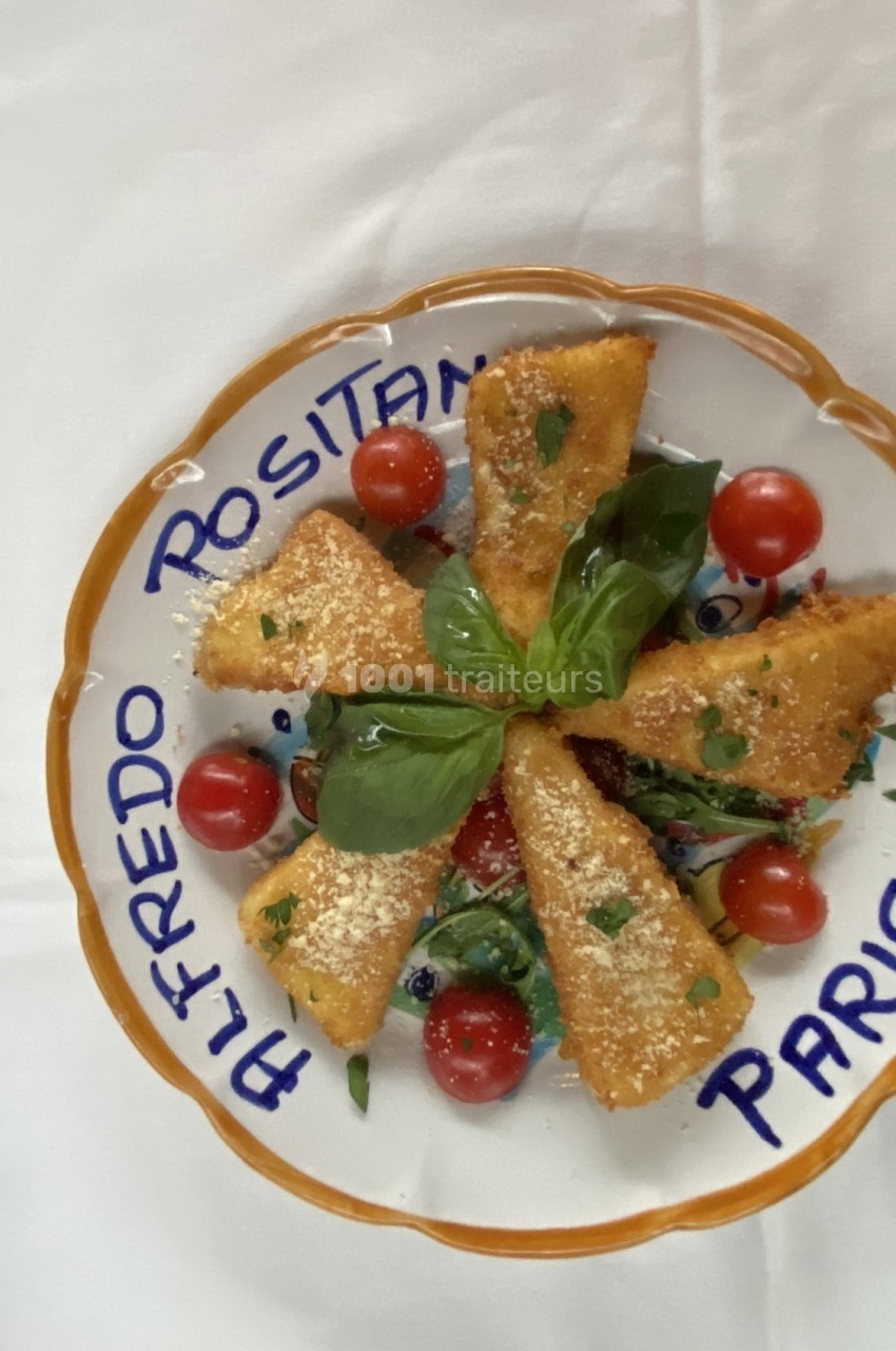 Assiette de croquettes dorées garnies de basilic, parmesan et tomates cerises, présentée sur une assiette décorative.