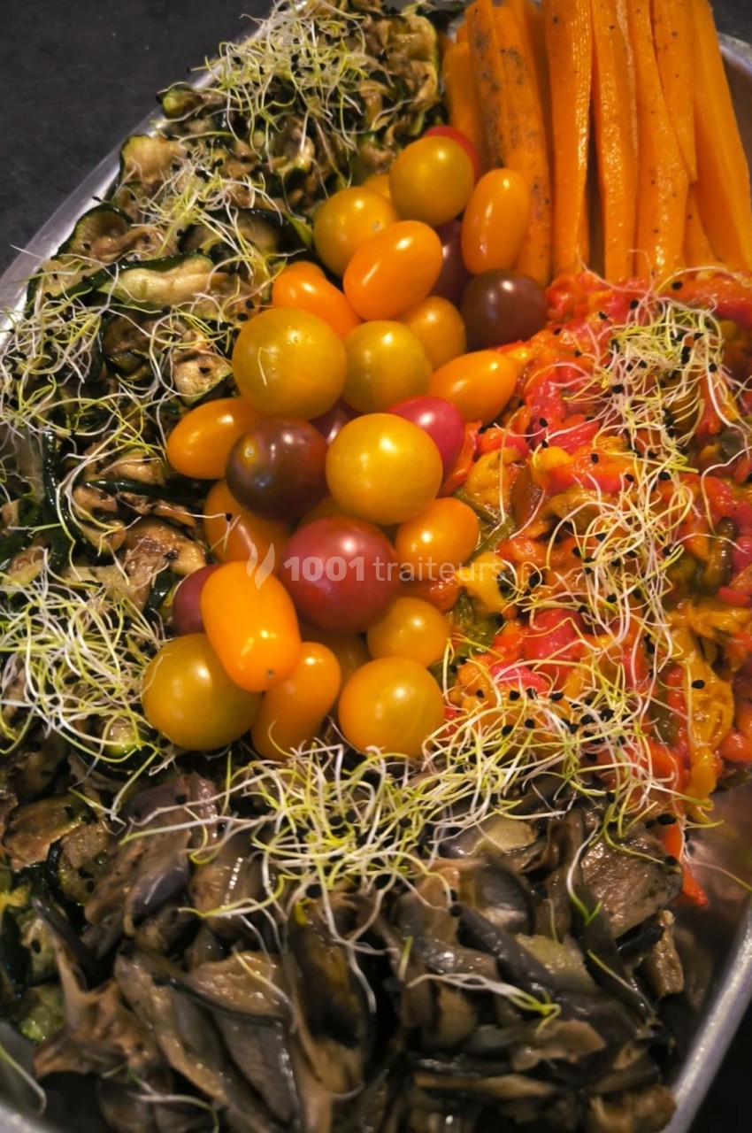 Plateau de légumes variés comprenant tomates cerises, carottes, courgettes, poivrons, champignons et germes.