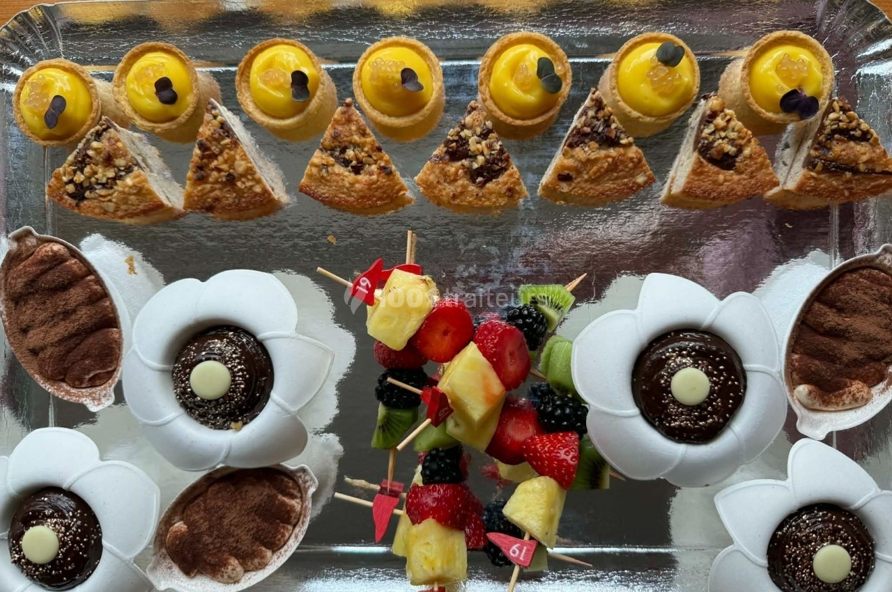 Plateau de desserts variés comprenant tartelettes, gâteaux, brochettes de fruits et pâtisseries décorées.