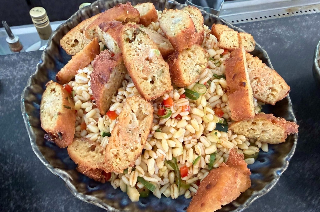 Salade de pâtes orzo garnie de croûtons dorés et de légumes colorés, servie dans un bol en céramique.