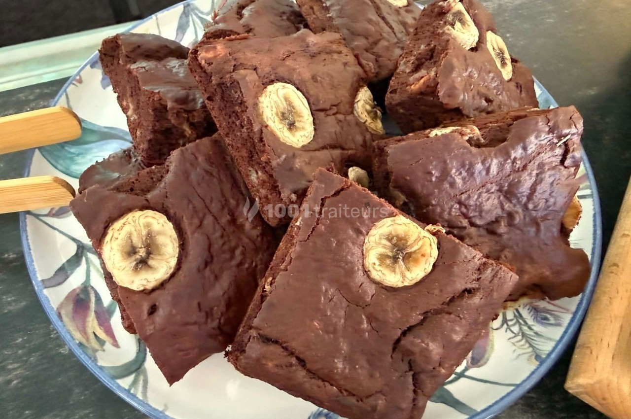 Assiette de brownies au chocolat garnis de tranches de banane, présentés sur une table.