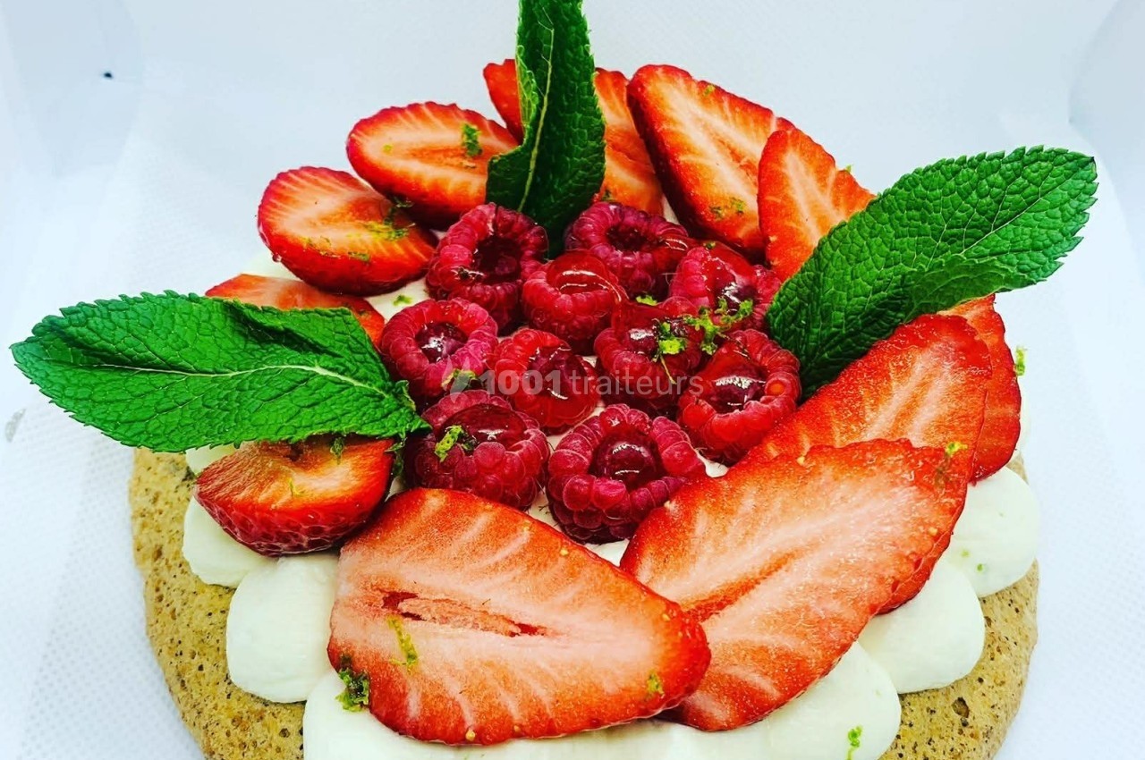 Gâteau décoré de fraises, framboises, feuilles de menthe et crème blanche sur une base biscuitée.