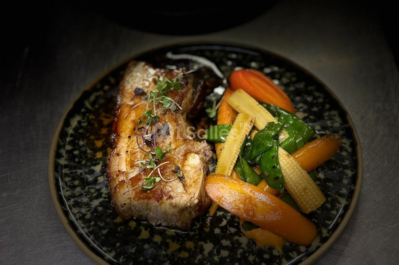 Plat de poisson grillé accompagné de légumes variés, dont carottes, mini-maïs et pois gourmands, servi sur une assiette…