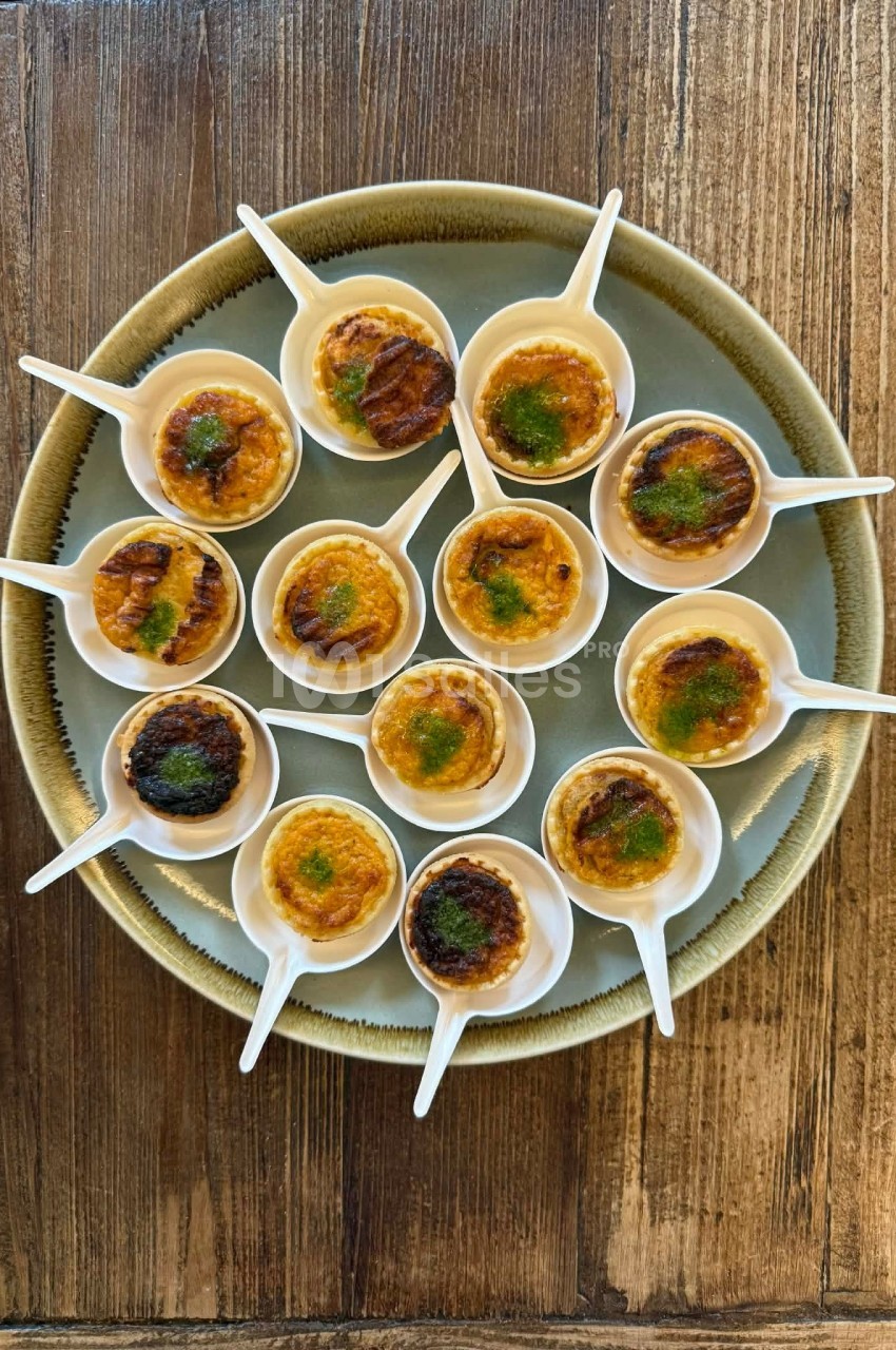Petites portions de crème brûlée servies dans des cuillères blanches sur une assiette ronde en bois.