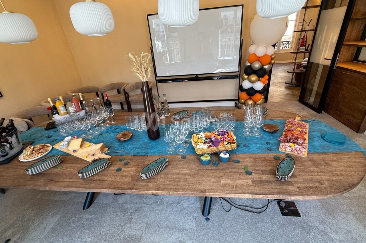 Table en bois décorée avec des plats apéritifs, des boissons, des verres et des décorations colorées dans une salle…