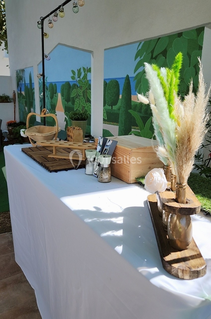 Table décorée avec des éléments naturels, comme des fleurs séchées et des paniers, dans un espace extérieur lumineux.