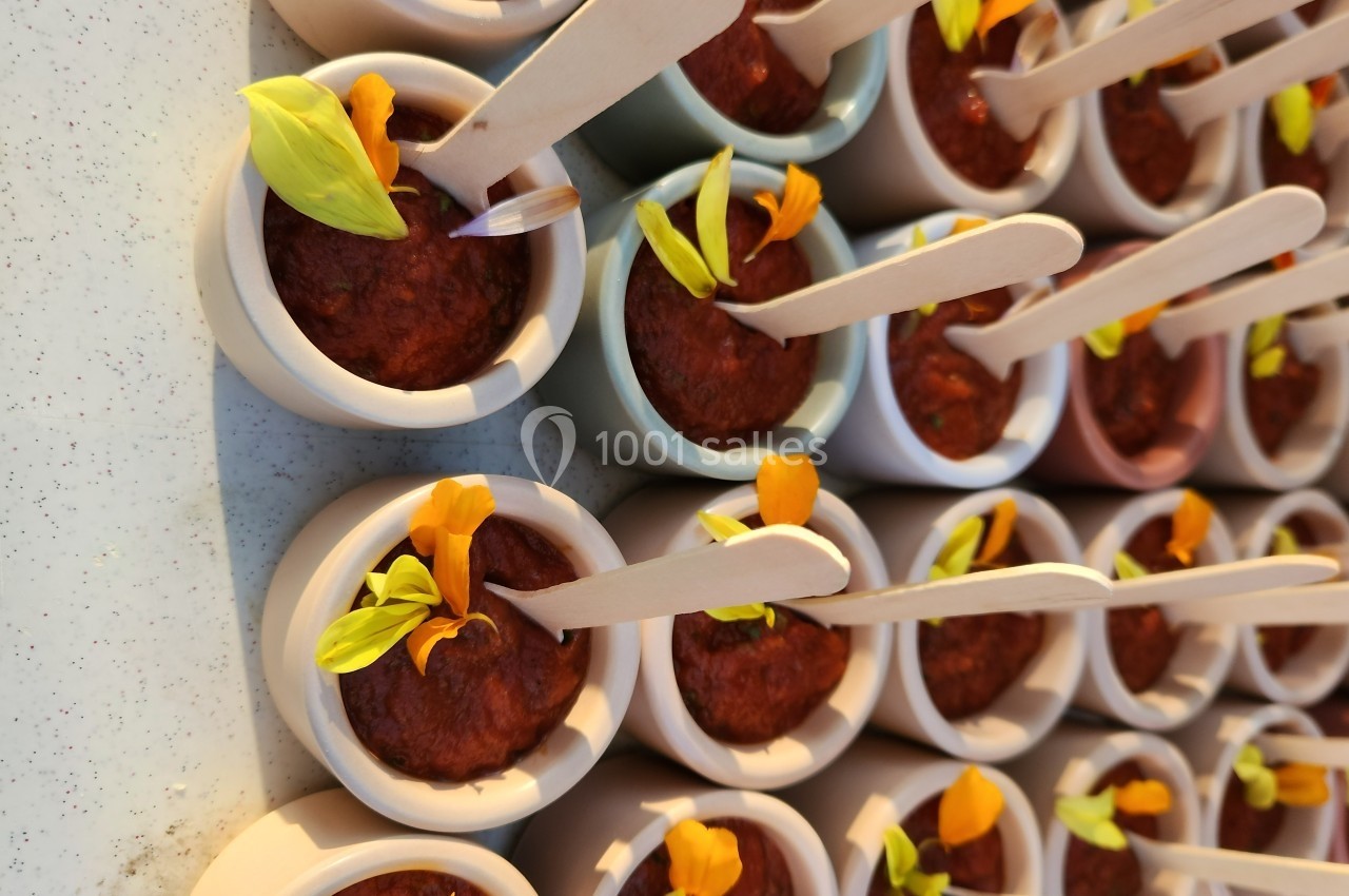 Petits pots de crème dessert garnis de pétales de fleurs jaunes et oranges, avec des cuillères en bois.