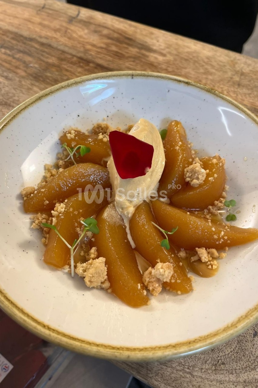 Assiette de poires caramélisées disposées en éventail avec une quenelle de crème et une pétale rouge au centre.