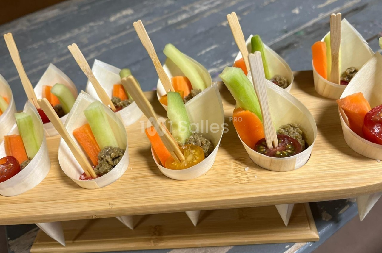 Coupelles en bois contenant des bâtonnets de légumes frais et des sauces, présentées sur un support en bois.