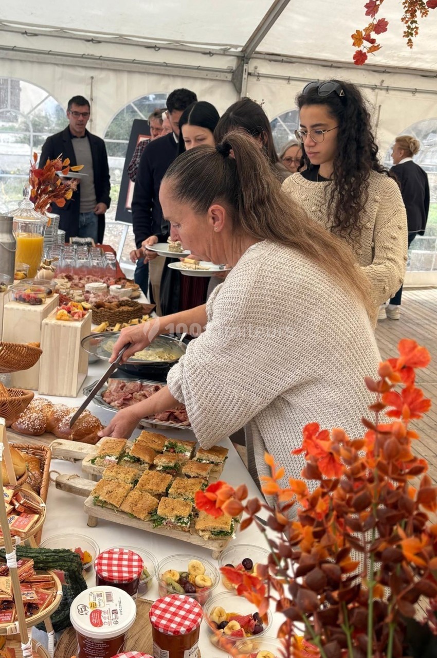 Des personnes se servent à un buffet varié sous une tente, décorée avec des éléments automnaux.