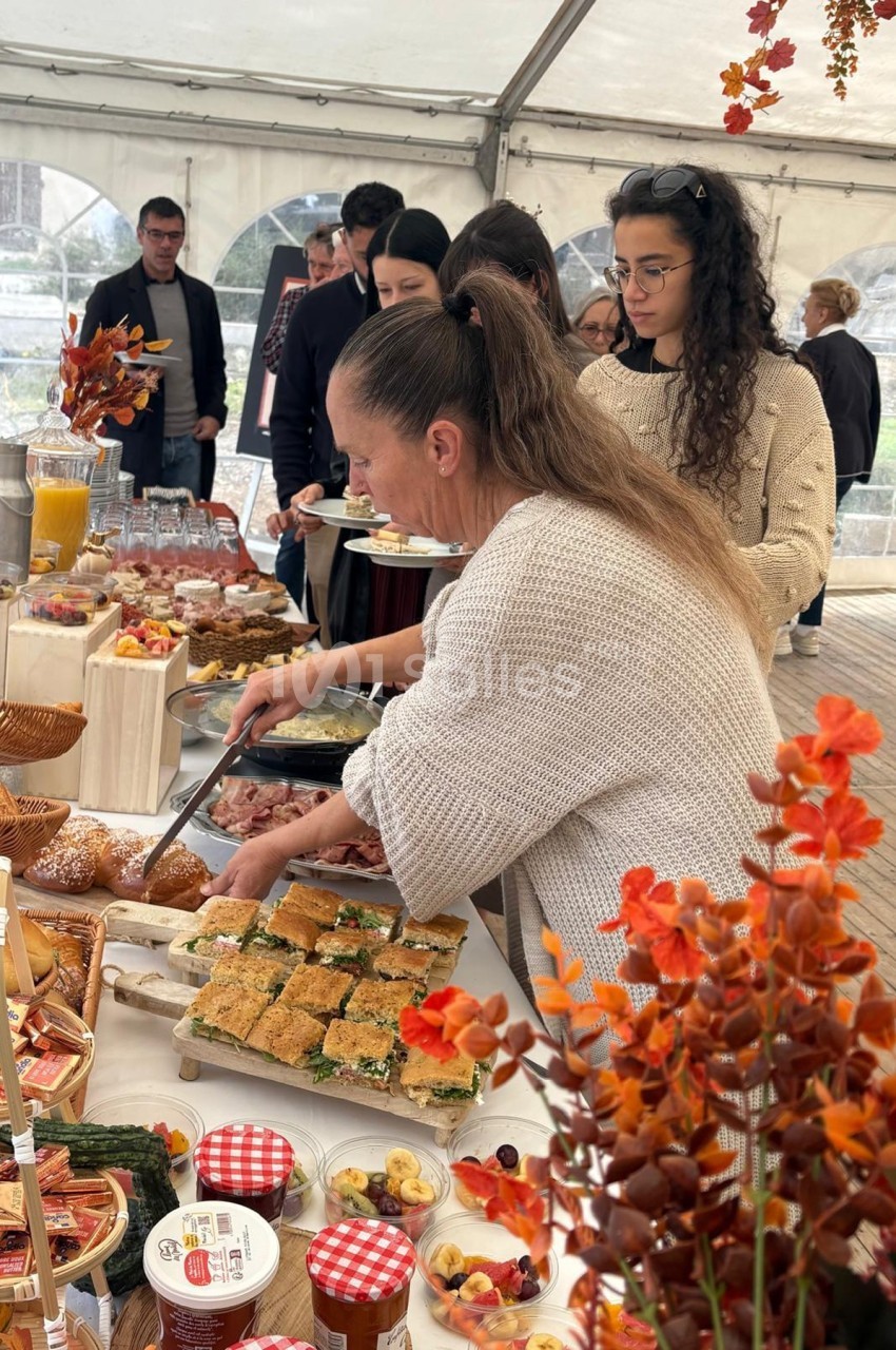 Personnes se servant à un buffet varié sous une tente, décorée avec des éléments automnaux.