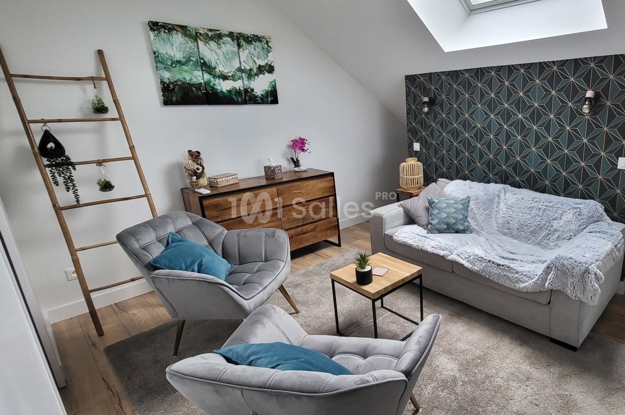 Salon moderne avec canapé gris, fauteuils, échelle décorative, commode en bois et mur accent à motifs géométriques.